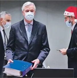  ?? Olivier Hoslet Associated Press ?? MICHEL BARNIER, center, the EU’s chief Brexit negotiator, carries a copy of the deal at a special meeting Friday at the European Council building in Brussels.