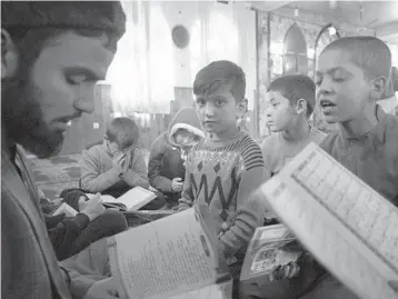  ?? MSTYSLAV CHERNOV/AP 2021 ?? Sanam, a bacha posh, or a girl living as a boy, center, sits among Afghan boys at a mosque in Kabul.