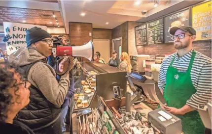  ?? AP ?? Activist Asa Khalif, left, demands change Sunday at the Starbucks in Philadelph­ia where two black men were arrested.