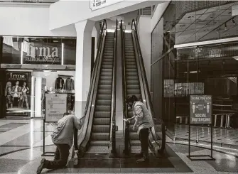  ?? Jon Shapley / Staff photograph­er ?? Workers clean an escalator at PlazAmeric­as mall on Friday. Despite parts of the local economy reopening, shaken consumer confidence could keep spending down, resulting in job losses.