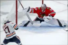  ?? JIM YOUNG — THE ASSOCIATED PRESS ?? The Oilers’ Connor McDavid, left, scores the winning goal against the Blackhawks’ Cam Ward during overtime of Sunday’s game in Chicago.