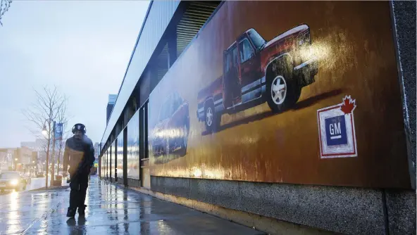  ?? COLE BURSTON/BLOOMBERG ?? A pedestrian walks past a GM mural in downtown Oshawa, Ont., on Monday. The job cuts there and in the U.S. are partly attributed to U.S. steel tariffs.