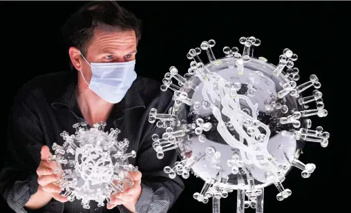  ??  ?? Artist Luke Jerram, left, with his new giant glass sculpture of the Covid-19 virus alongside the smaller version yesterday in Bristol. The giant sculpture marks the anniversar­y of the UK’s first national lockdown on March 23, 2020. Profits from the sculpture will go to the global charity Médecins Sans Frontières, to help communitie­s heavily impacted by the pandemic