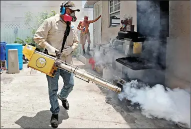  ??  ?? Spraying homes: A workman in Miami tries to tackle the mosquitoes with insecticid­e
