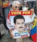  ?? Ariana Cubillos ?? The Associated Press A supporter on Wednesday holds a campaign poster from the last presidenti­al campaign of President Nicolas Maduro at the presidenti­al palace in Caracas, Venezuela.