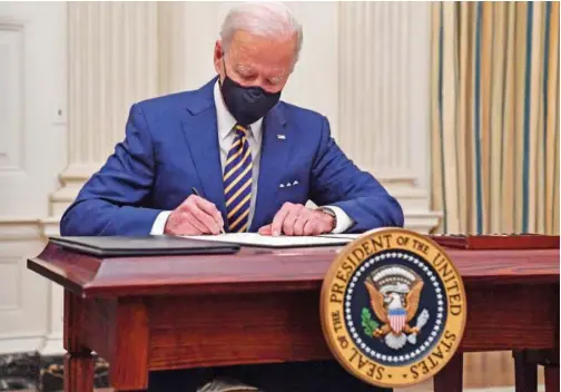  ?? Agence France-presse ?? US President Joe Biden signs executive orders for economic relief to COVID-HIT families and businesses in the State Dining Room of the White House in Washington, DC.