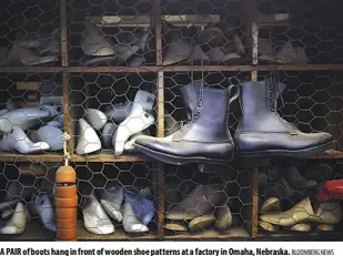  ?? Bloomberg News ?? A pair of boots hang in front of wooden shoe patterns at a factory in Omaha, Nebraska.