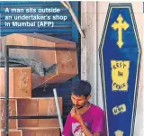  ??  ?? A man sits outside an undertaker’s shop in Mumbai (AFP)