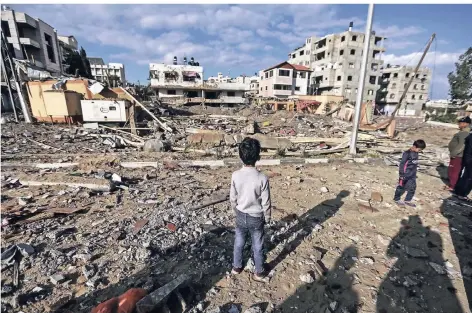  ?? FOTO: DPA ?? Palästinen­ser inspiziere­n ein zerstörtes Gebiet nach einem Luftangrif­f. Israel hat in Gaza drei Gebäude der Hamas zerstört.