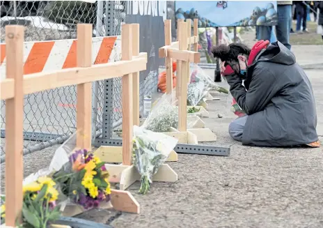  ?? Helen H. Richardson, The Denver Post ?? Starr Samkus, a King Soopers employee, cries on Tuesday in front of 10 wooden crosses erected next to the fence surroundin­g the grocery store in Boulder. Samkus knew three of those who died in the mass shooting. Hundreds of people have stopped by, and many have left flowers as they paid their respects.