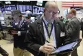  ??  ?? NEW YORK: Trader Jeffrey Vazquez, foreground, works on the floor of the New York Stock Exchange yesterday.
— AP (See Page 23)