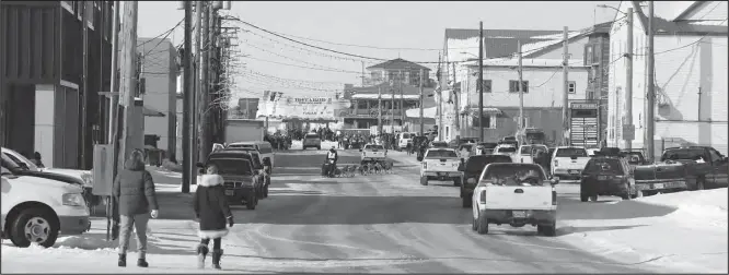  ?? Photo by Diana Haecker ?? TOWARD THE FINISH LINE— Anna Berington mushes her dog team down Nome’s Front Street to the burled arch that is the finish line of the 1,000-mile race.