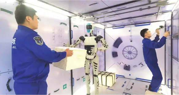  ?? Zhang Qi ?? The Taikobot prototype was tested in a space station mock-up. It could use a hammer and electric screwdrive­r in one hand and carry a package in the other. It followed crew members, delivering tools and taking photos