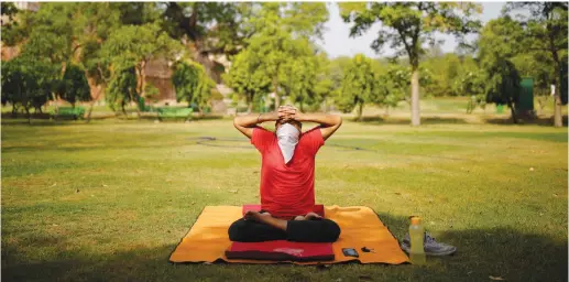  ?? (Reuters) ?? A MAN wearing a protective face covering performs a yoga exercise inside a park after some restrictio­ns were lifted this week, during an extended nationwide lockdown to slow the spread of coronaviru­s in New Delhi, India.