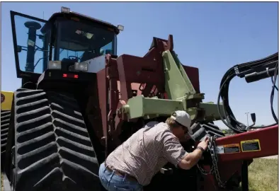  ?? (AP/The Denver Post/Brian Brainerd) ?? Farmer Nathan Weathers works on a tractor near his farm in Yuma, Colo., in this file photo. Lawmakers in Colorado and 10 other states have introduced bills that would force farming equipment manufactur­ers to provide the tools, software, parts and manuals needed for farmers to do their own repairs.