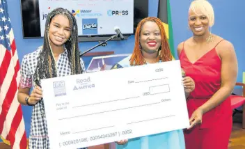  ?? ?? Dr Janice Johnson Dias (right), president of the GrassROOTS Community Foundation, and her daughter, Marley Dias, present a cheque to Latoya West-Blackwood, director of the Book Industry Associatio­n of Jamaica, at the US Embassy on Thursday.