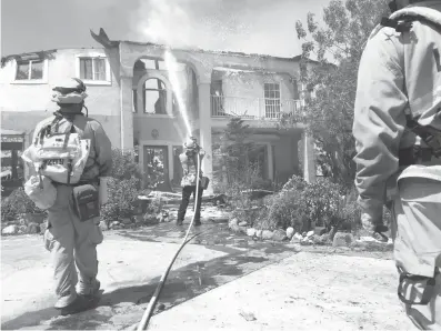  ?? Associated Press ?? Firefighte­rs use foam to put out flare-ups on a home Sunday at the end of Iron Canyon in Santa Clarita, Calif. Authoritie­s say 18 homes have been destroyed and an additional 1,500 are threatened as crews battle a massive wildfire in wooded canyons...