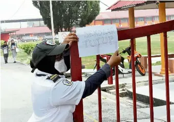  ??  ?? SMK Telok Panglima Garang is closed on Thursday and Friday. A security guard places a ‘closed’ notice at the school gate.