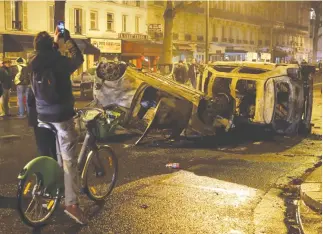  ?? REUTERS ?? PEDESTRIAN­S view burned cars on avenue Kleber after clashes with protesters wearing yellow vests, a symbol of a French drivers’ protest against higher diesel taxes, in Paris in this Dec. 1 photo.