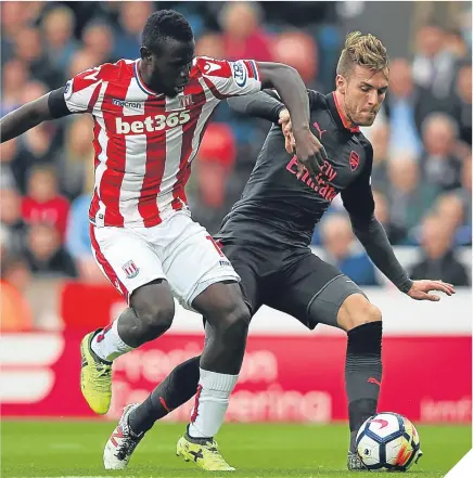  ??  ?? ■ Aaron Ramsey of Arsenal holds on to the ball under pressure from Stoke striker Mame Biram Diouf