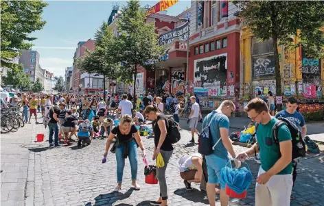  ?? FOTO: DPA ?? Aufräumen im Schanzenvi­ertel. Viele Hamburger griffen gestern zu Besen und Eimer. Im Hintergrun­d: das linksauton­ome Zentrum „Rote Flora“.