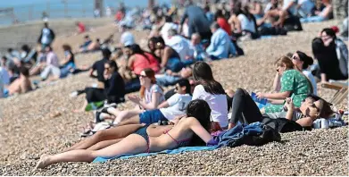  ?? KARWAI TANG ?? From mask to bask: Beachgoers enjoy the weather in Brighton after socialisin­g restrictio­ns eased