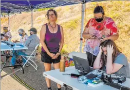  ?? Daniel Kim The Associated Press ?? Helina Thorp, right, 14, unsuccessf­ully tries to log in to distance-learning classes Tuesday at the El Dorado Fairground­s in Placervill­e, Calif., as her mother, Virginia Thorp, attempts to call school officials during a public safety power shutoff.