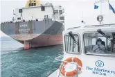  ??  ?? The Mission to Seafarers boat travels past a Greeceflag­ged bulk carrier anchored off Hong Kong.