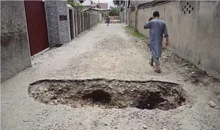  ??  ?? A man walking at a back street with a hole dug in the ground to restrict movements in the Soura locality in Srinagar recently. AFP PIC