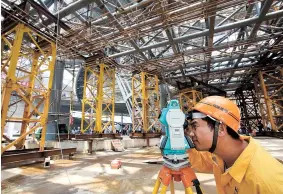  ??  ?? A worker observes the condition of the cantilever after removing the bracing system yesterday at the constructi­on site of Shanghai Planetariu­m. — Wang Rongjiang