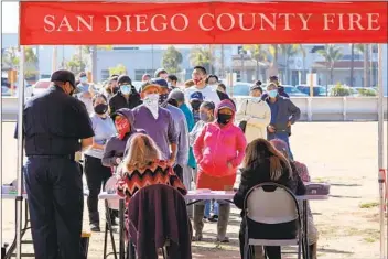  ?? CHARLIE NEUMAN ?? Farm workers line up at the Carlsbad Strawberry Company on Saturday to receive a dose of the Moderna vaccine administer­ed by Cal Fire firefighte­rs and other county fire agencies.