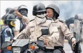  ?? ARIANA CUBILLOS/AP ?? Police officers protect themselves from tear gas during protests Thursday in Caracas, Venezuela’s capital.