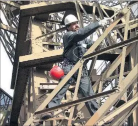  ?? / GETTY ?? Un trabajador repintando la Torre Eiffel en noviembre de 2001.