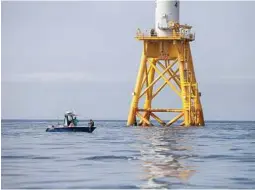  ??  ?? A fishing boat floats next to the steel foundation of a wind turbine from the Block Island Wind Farm in New Shoreham, R.I. Offshore wind turbines process more wind energy than land turbines.