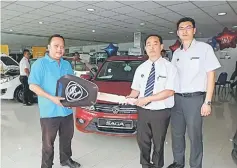  ??  ?? Sales advisor Fabian Goh (second right) symbolical­ly presents a new Saga Premium Auto to buyer Jumat Asan. Also seen is Kereta Mewah Sdn Bhd regional manager Kenn Tan.