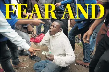  ?? Picture: REUTERS ?? PLEADING: A man holds his South African identity document after being attacked by a mob in Pretoria