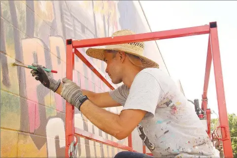  ?? ?? Lucas Aoki, a native of Argentina, paints a mural at Prairie Grove Public Library last week. He has lived in the Austin, Texas, area since 2007.