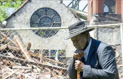  ?? Pam Panchak/Post-Gazette ?? Pastor Frank Tillman Jr. walks by the fallen Christian Fellowship Center and the Church of God in Christ, in Woods Run.