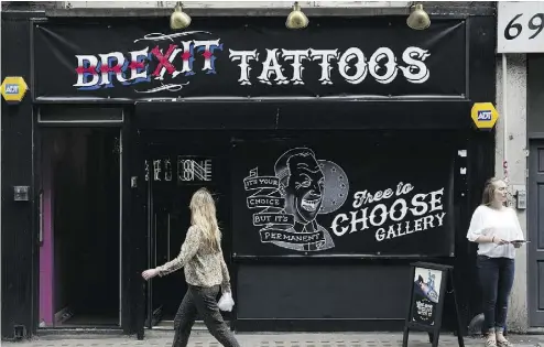  ?? JUSTIN TALLIS / AFP / GETTY IMAGES ?? A woman walks past a pop-up store offering satirical pro-Brexit tattoos for free on Wednesday in London. The shop, open for one day only, was organized by the pro-European Union Remain campaign ahead of Thursday’s referendum.