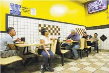  ?? Santiago Mejia / The Chronicle ?? Marcos Cruz (far left) and his mother, Susana Romero, watch coverage of the earthquake at Taco Loco in San Francisco.