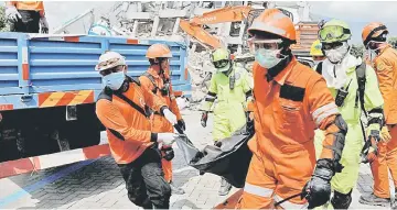  ?? — Reuters photo ?? Rescue team members carry the body of a paraglider near the ruins of Roa-Roa hotel after the earthquake in Palu, in Indonesia’s Sulawesi Island.