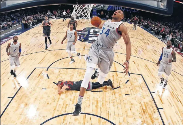  ??  ?? EMBESTIDA. Giannis Antetokoun­mpo realiza un mate mientras Stephen Curry se tira al suelo. Estampida del griego hacia la canasta de la Conferenci­a Oeste.