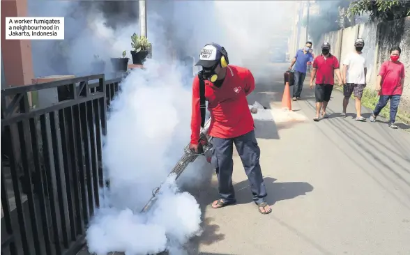  ??  ?? A worker fumigates a neighbourh­ood in Jakarta, Indonesia