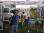  ?? ADAM DODD — THE NEWS-HERALD ?? Patrons peruse paintings and other artwork at the 2019 Chardon Arts Festival.