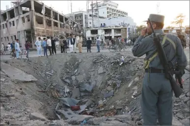  ?? The Associated Press ?? A member of Afghanista­n’s security forces stands next to a crater created by a massive explosion in front of the German Embassy in Kabul on Wednesday. The suicide truck bomb hit a highly secure diplomatic area, killing 90 people and wounding hundreds more.