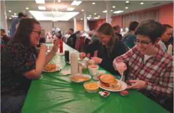  ?? AP PHOTO/JESSIE WARDARSKI ?? From left, Laura Kuster, Miranda Crotsley, and Hollen Barmer eat fish sandwiches, homemade perogies, and macaroni and cheese Friday at the St. Maximilian Kolbe Catholic Church fish fry in the West Homestead neighborho­od of Pittsburgh.