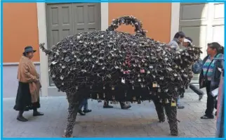  ??  ?? Peatones observan la escultura del cerdo en La Paz, Bolivia