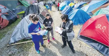  ?? ARLEN REDEKOP ?? From left, Joyce, Crystal Cardinal and Gina Baptis go over notes at the Main Street homeless camp. Vancouver says the tent city is blocking the developmen­t of a mixed-use building with 26 units of social housing.