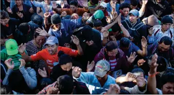  ?? AP PHOTO/RODRIGO ABD ?? CENTRAL AMERICAN MIGRANTS, part of the caravan hoping to reach the U.S. border, pray at a temporary shelter in Tijuana, Mexico, Friday. The number of migrants in the city could approach 10,000 over the next six months.