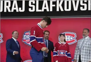  ?? RYAN REMIORZ — THE CANADIAN PRESS VIA AP ?? Juraj Slafkovsky puts on a Canadiens jersey after being selected as the top pick in the NHL draft Thursday.